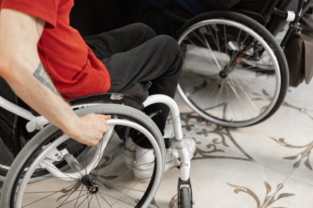 L'immagine rappresenta un disabile sulla sedia a rotelle. Non è visibile il volto ma solo le braccia e l'addome. Ha una maglietta rossa. La legge di bilancio ha previsto delle novità per l'ADI 2025