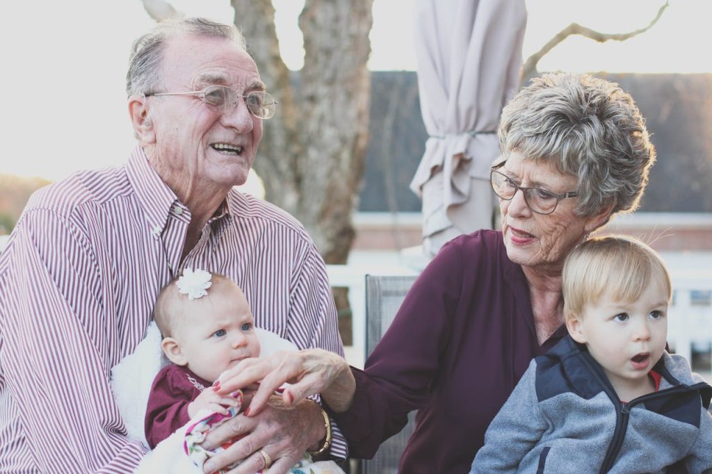 Due nonni tengono in braccio due bambini molto piccoli, fratello e sorella entrambi biondi