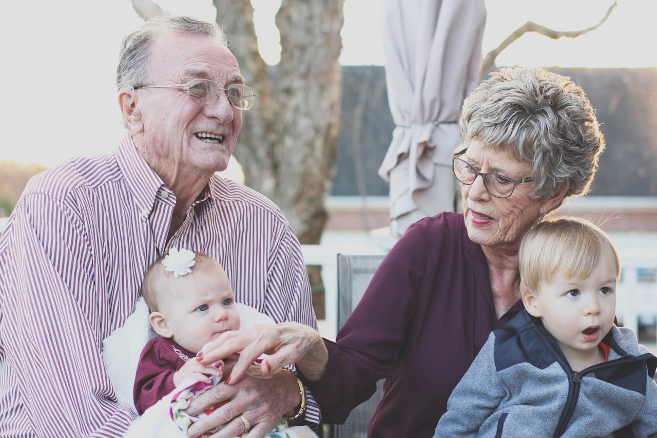 Due nonni tengono in braccio due bambini molto piccoli, fratello e sorella entrambi biondi
