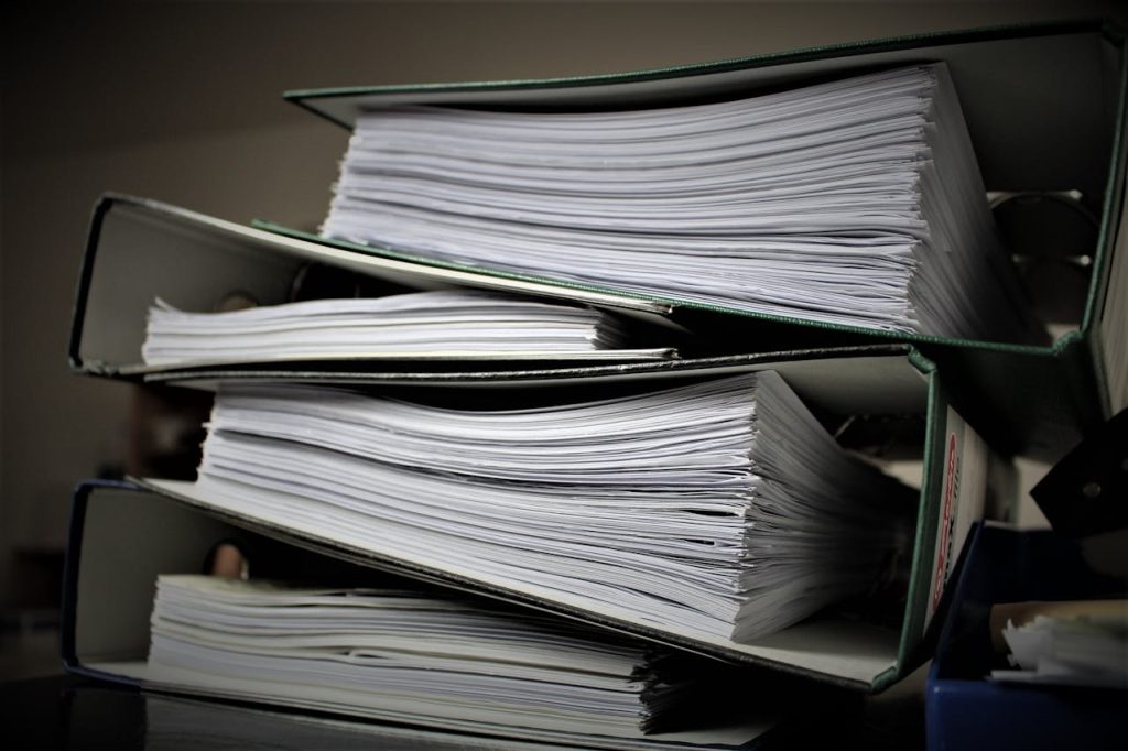 Tra faldoni con documenti sono appoggiati uno sopra l'altro sul tavolo di una scrivania